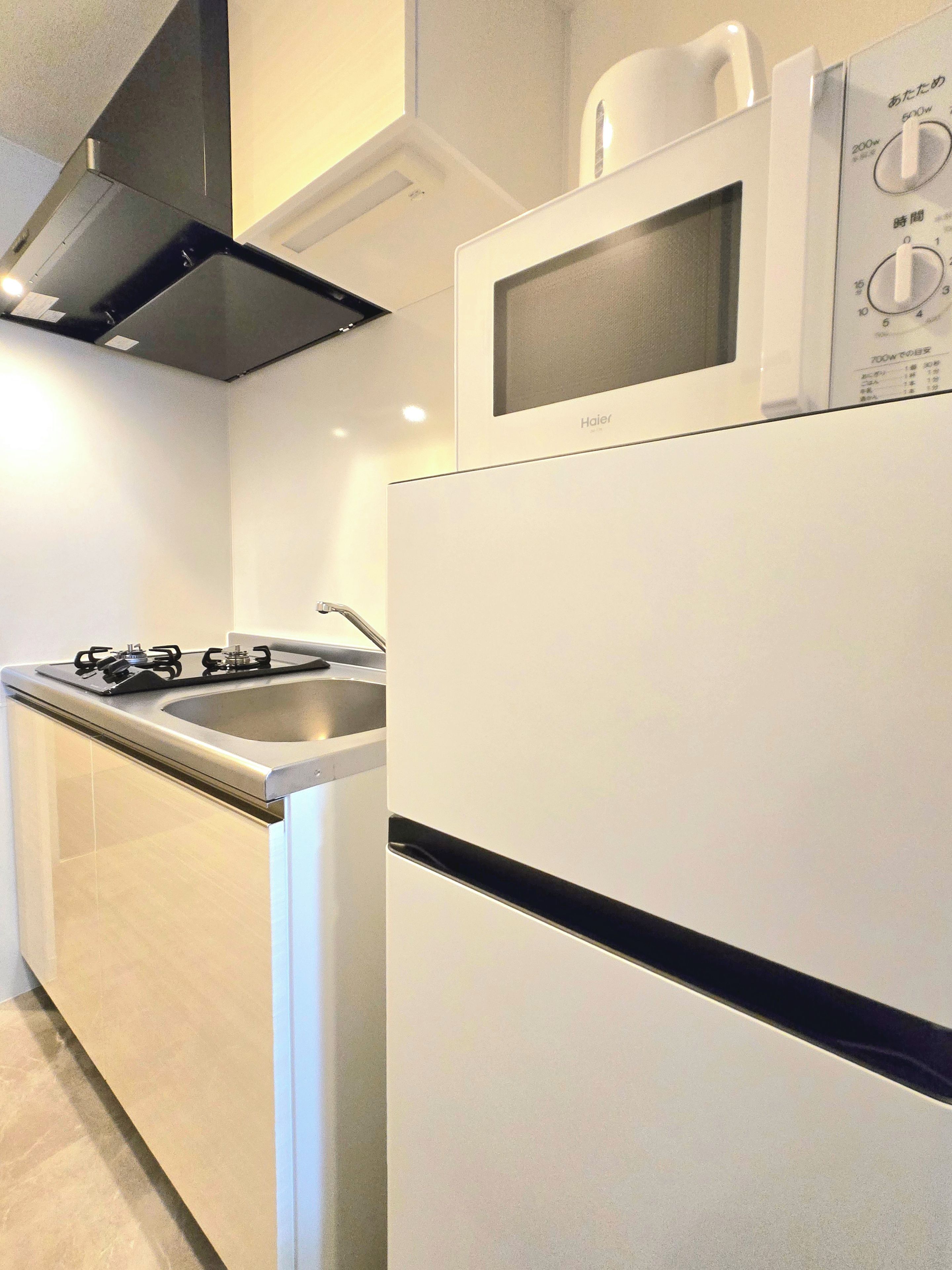 A kitchen with a white refrigerator, a microwave, and a gas stove.