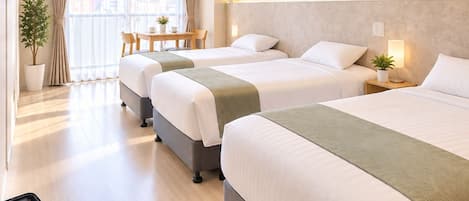 A hotel room with two beds, a dining area, and a suitcase on the floor.