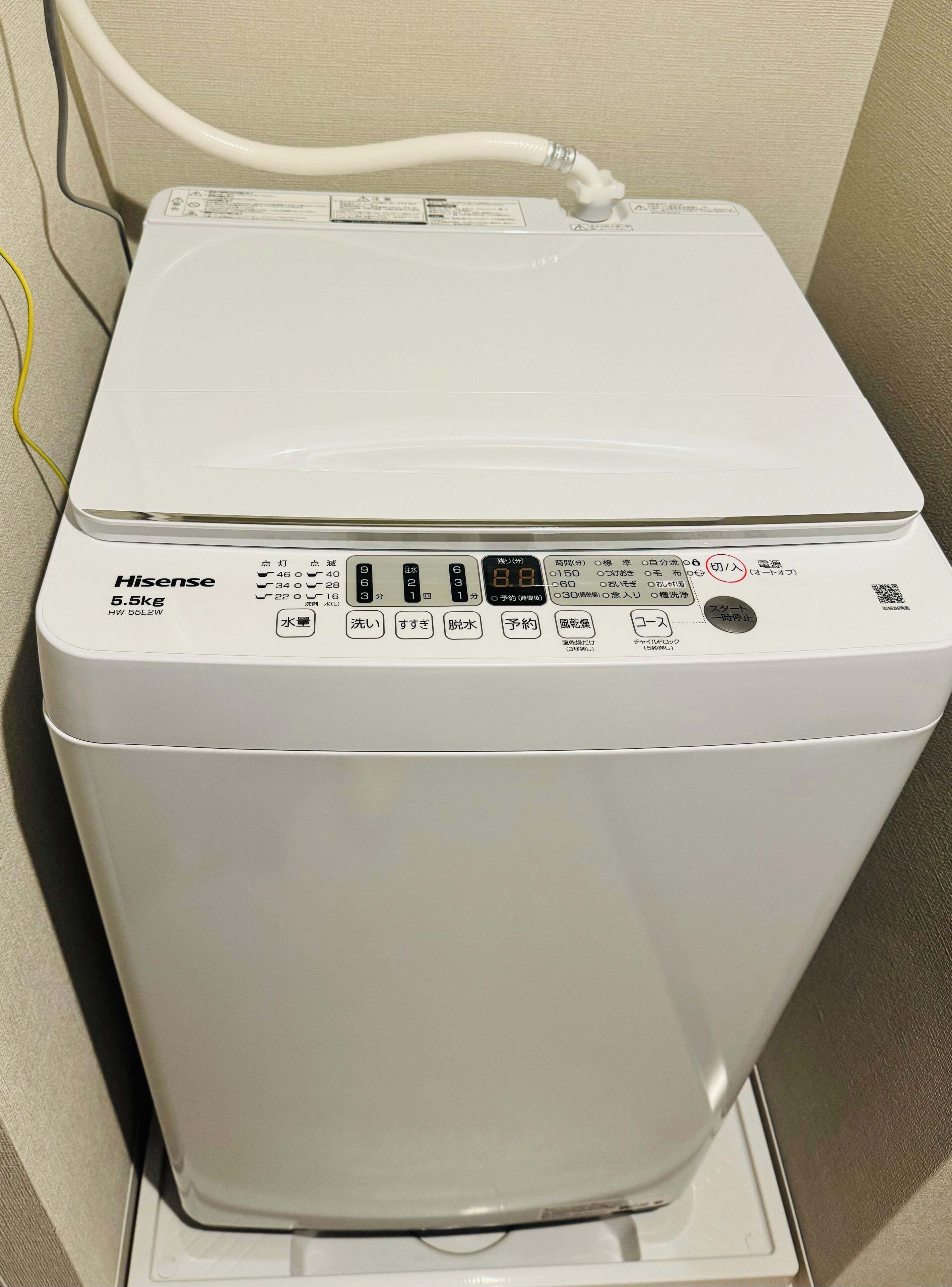 Una lavadora Hisense de 5.5 kg con carga frontal, pantalla digital, panel de control y cable de alimentación.