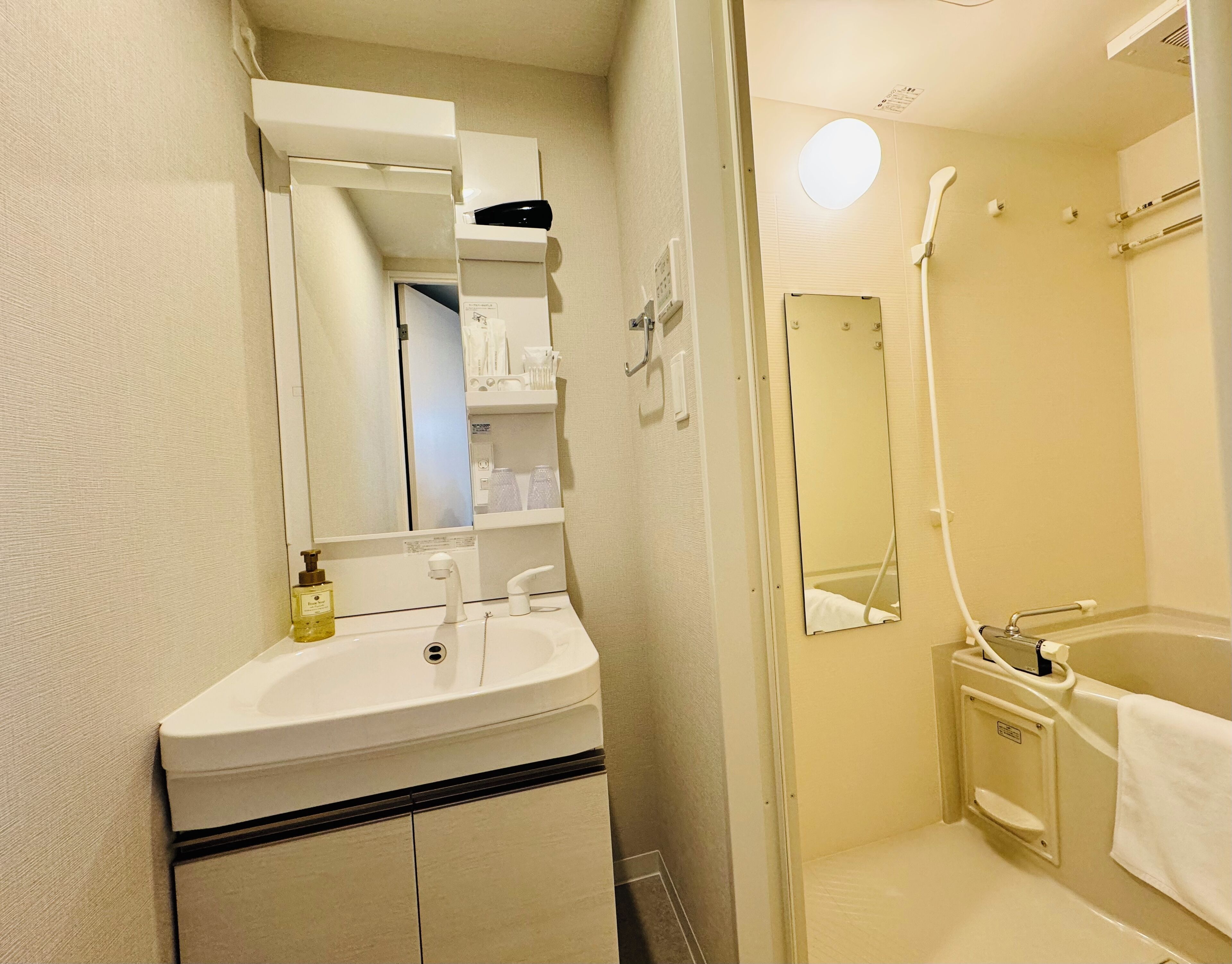 A bathroom with a sink, mirror, and shower.