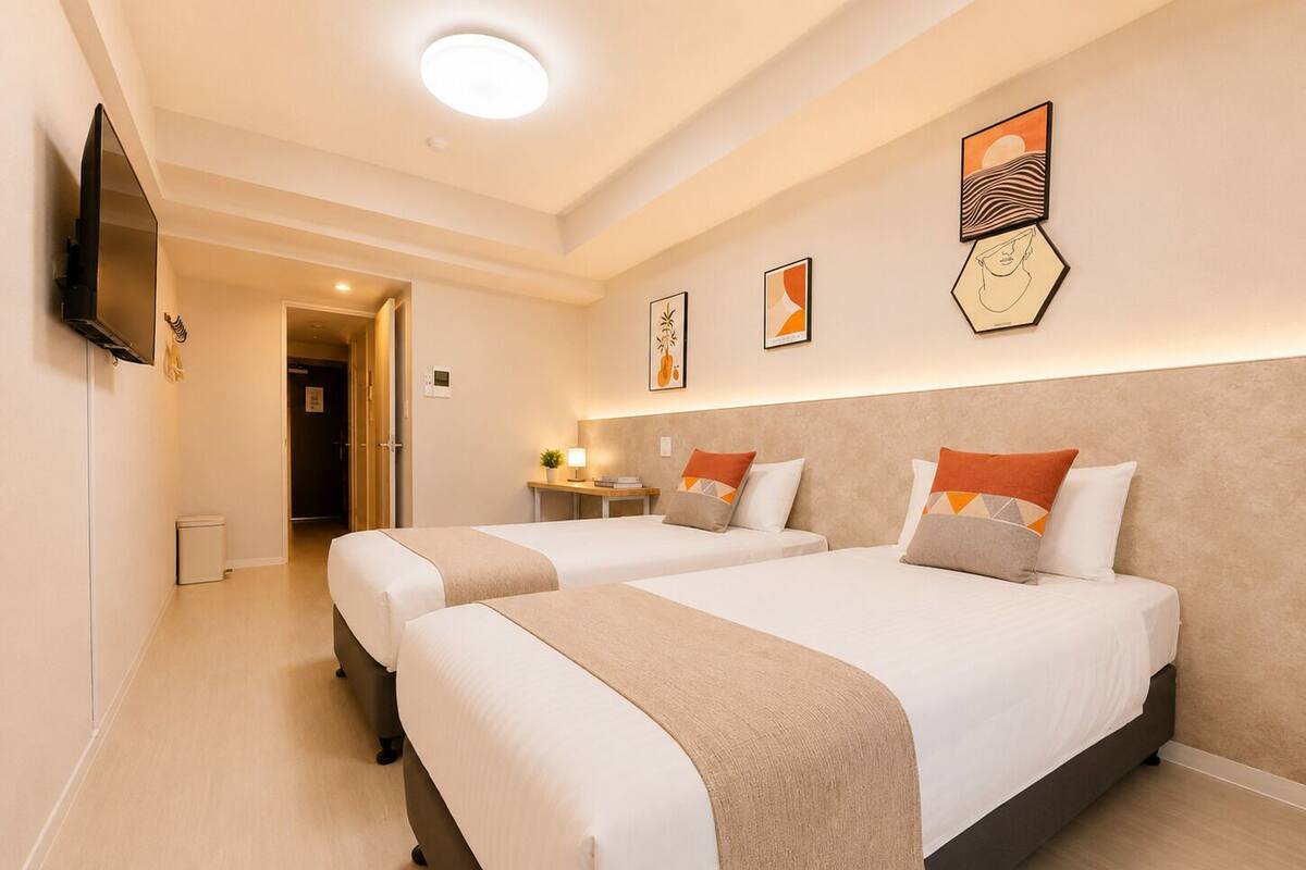 A hotel room with two beds, a TV, and artwork on the wall.