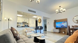 TV, books - Al Reef Retreat: Your 1BR w/ Sofa Beds, Pool & Gym (Abu Dhabi)