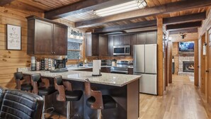 A modern kitchen with dark wooden cabinets, stainless steel appliances, and a central island with bar stools.