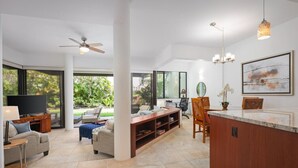 A spacious living area with a TV, seating, and a kitchen counter.
