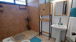 Een badkamer met toilet, bidet, wastafel, spiegel en kast.