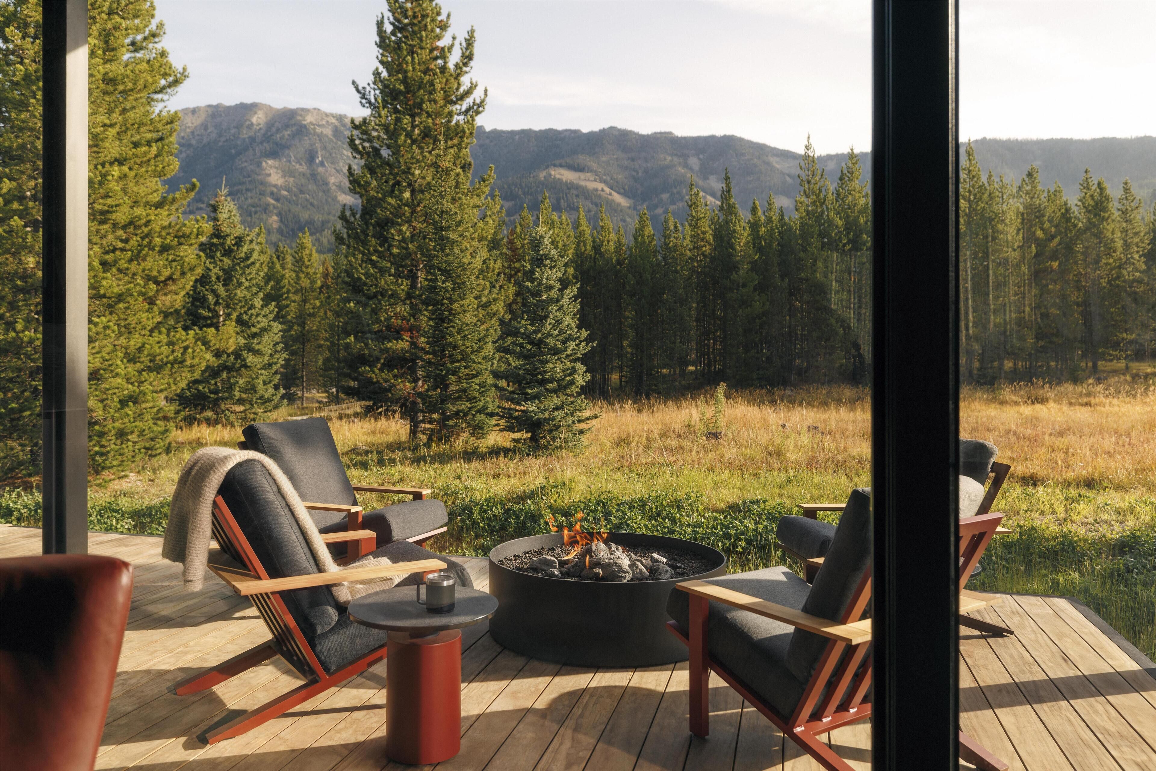 A deck with outdoor seating, a fire pit, and a view of a forest and mountains.