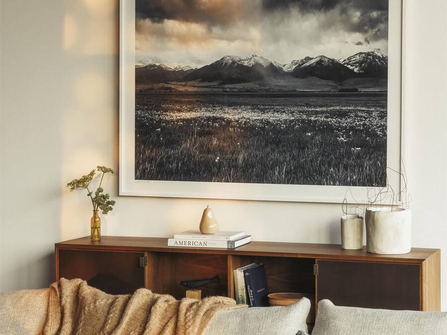 A living room with a large framed landscape painting, a wooden console table, and a sofa with cushions.