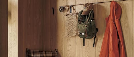 Een houten bank met een geruit kussen, een groene thermosfles en een paar laarzen.