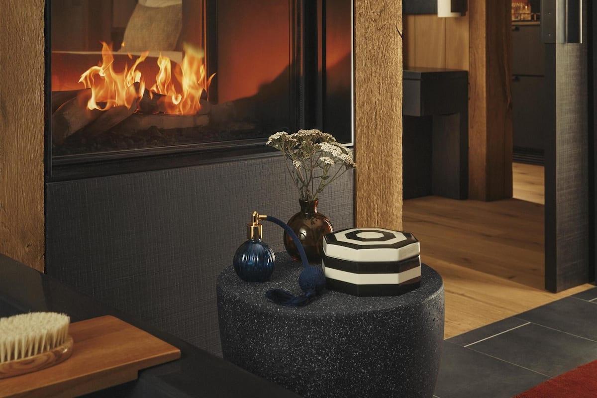 A modern living room with a fireplace, a small round table with decorative items, and a wooden floor.