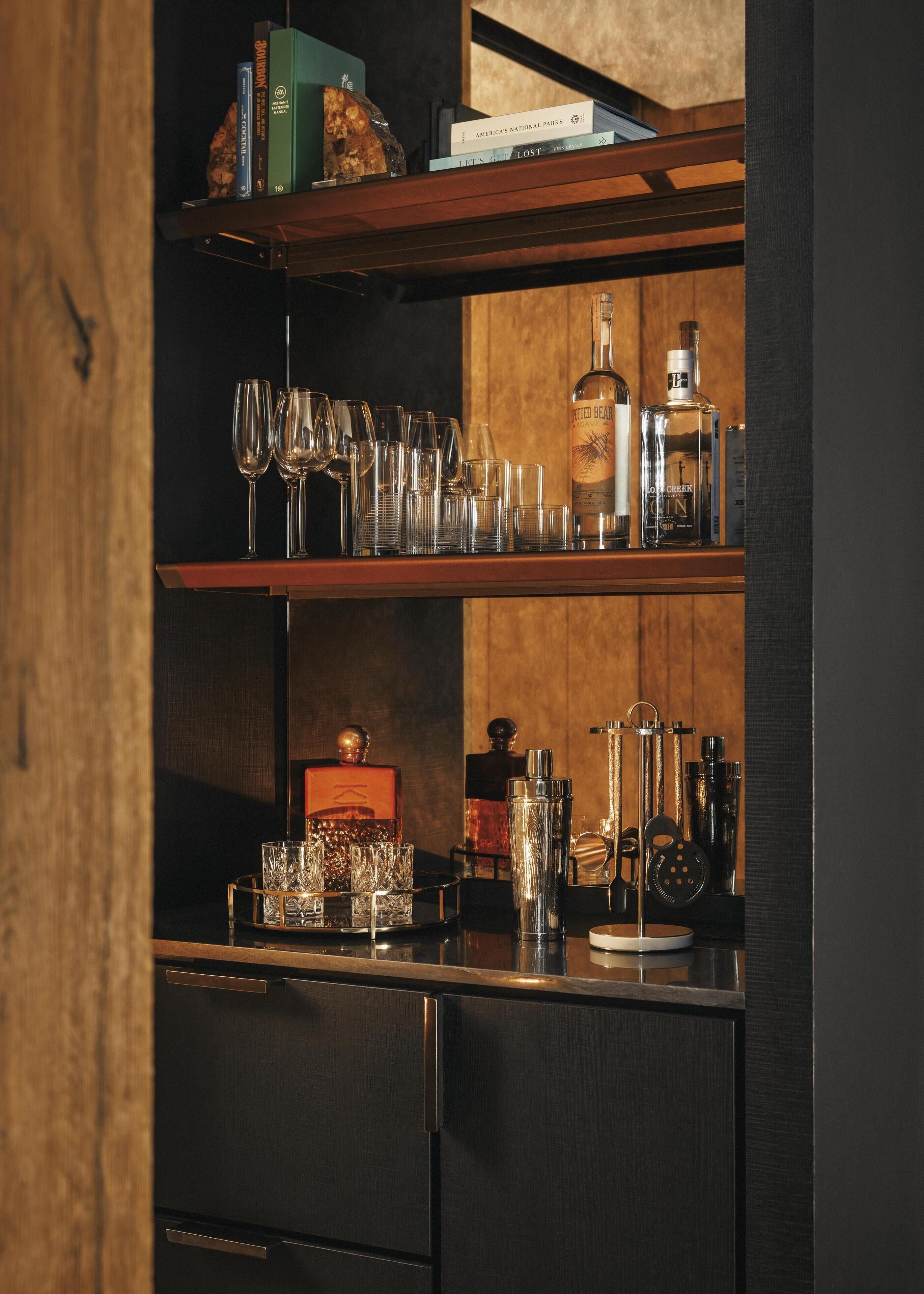 Zona de bar con estantes que contienen libros, vasos y botellas.