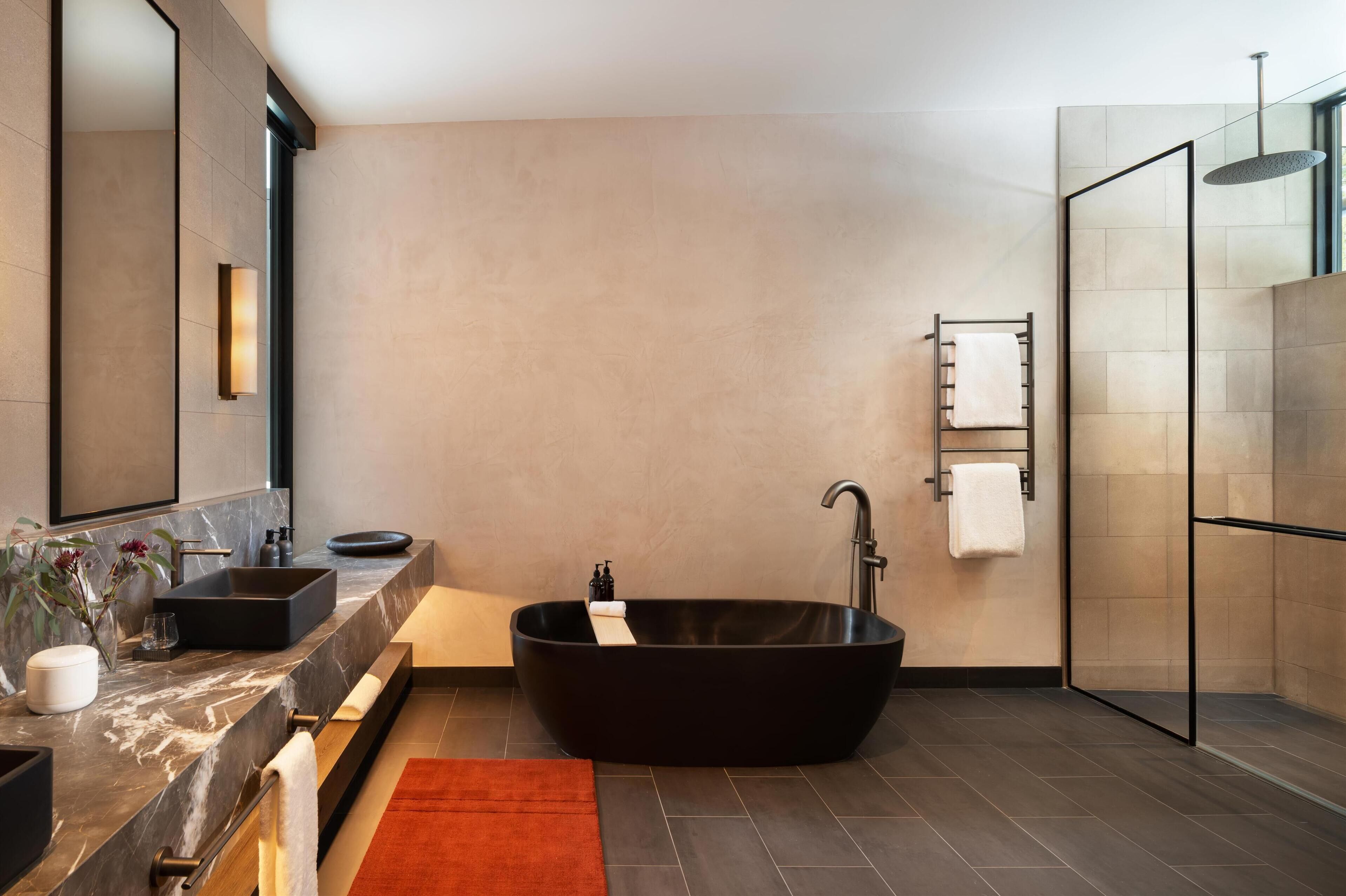 A modern bathroom with a freestanding bathtub, a large mirror, and a glass-enclosed shower.