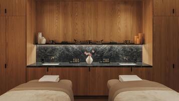 Ein modernes Badezimmer mit Holzschränken, einer Marmorarbeitsplatte und einem Waschbecken. Zwei Betten mit weißer Bettwäsche und eine Blumenvase stehen auf der Arbeitsplatte.