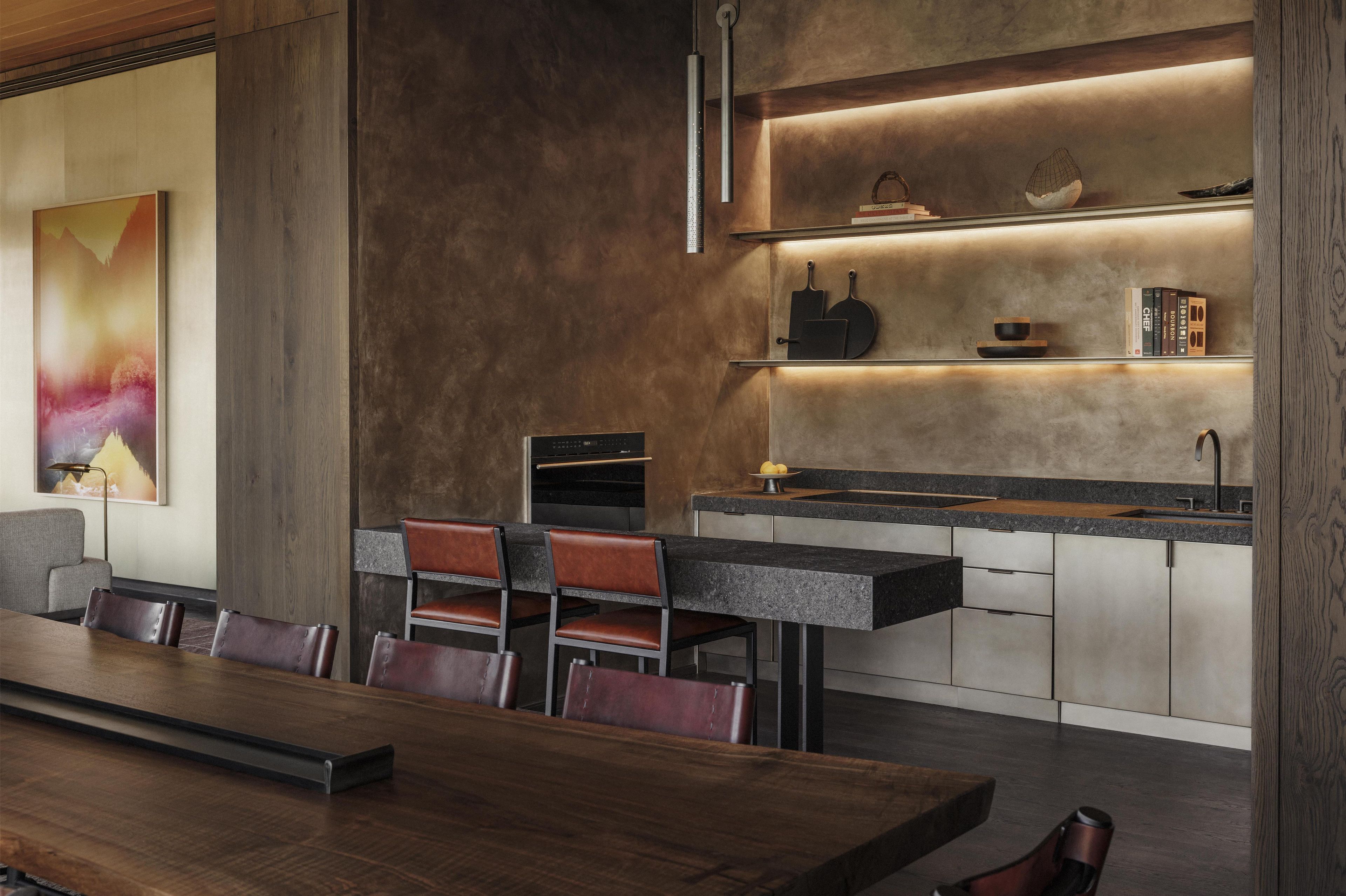 A modern kitchen with a central island, built-in appliances, and a dining area with a long table and chairs.