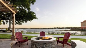 A circular stone fire pit with three Adirondack chairs around it, overlooking a body of water. - Charming villa with WiFi, AC, fitness room in fabulous Orlando (Orlando)