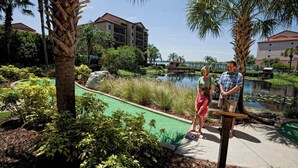 A pool area with a green water slide, surrounded by palm trees and a building in the background. - Charming villa with WiFi, AC, fitness room in fabulous Orlando (Orlando)