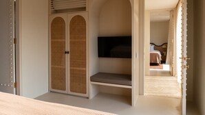 Une chambre dotée d’une grande armoire, d’un lit et d’un téléviseur fixé au mur.