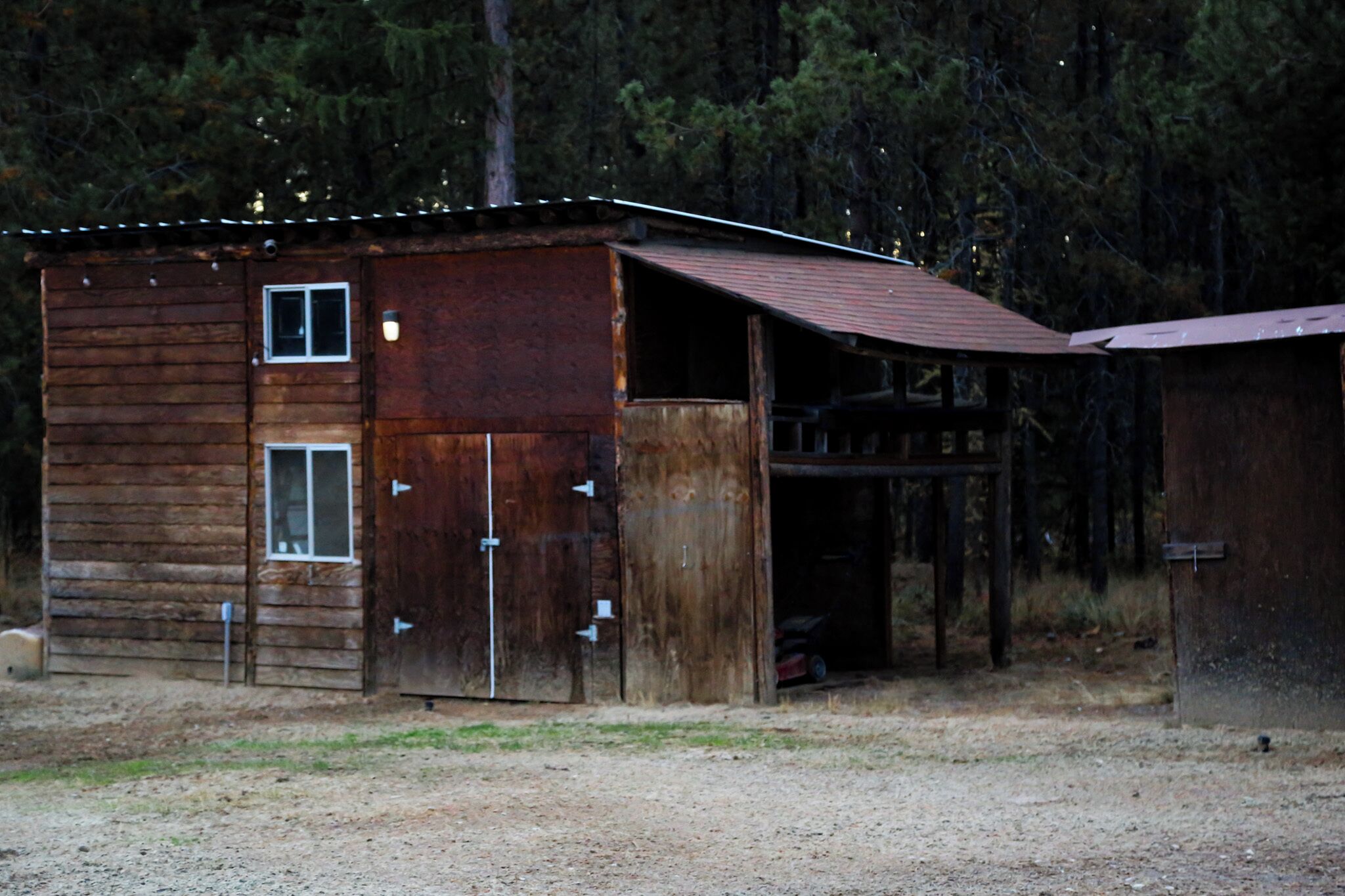 A rustic wooden cabin with a metal roof, a garage, and a covered area.