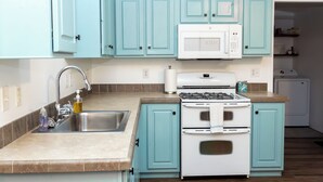 Una cocina con armarios color turquesa, una estufa blanca y un microondas.