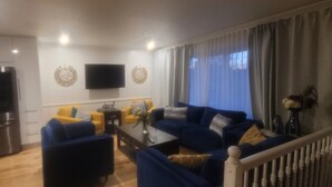 A modern living room with a sofa set, a coffee table, and a flat-screen TV mounted on the wall.