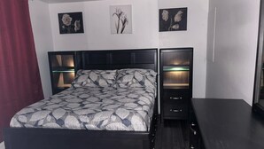 A bedroom with a bed, bedside tables, and wall-mounted lamps.