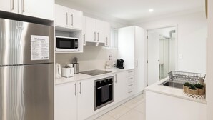 A modern kitchen with white cabinetry, stainless steel appliances, a microwave, and a built-in oven. - Smart Suites Self Check-in Apartments - 31A Freney (Rocklea)