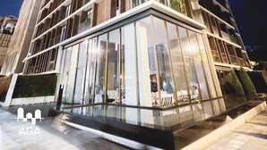 A modern high-rise building with a distinctive geometric facade, large windows, and a reflective glass entrance. - Loft in Barranco | Sea View (Barranco)