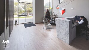 A modern reception area with a marble counter, a Christmas tree, and a large window offering a view of parked cars and greenery outside. - Loft in Barranco | Sea View (Barranco)