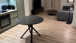 A modern living room with a round black table, a grey sofa, a flat-screen TV, and a coffee machine. - Cozy 1 bed apartmrnt  Luton Airport (Luton)