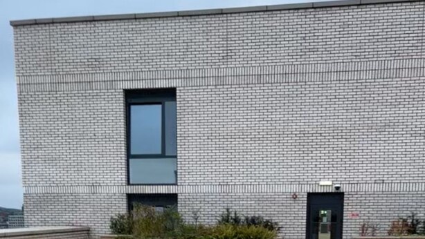 A modern building with a brick facade, a flat roof, and a paved courtyard with artificial grass and a small garden area. - Cozy 1 bed apartmrnt  Luton Airport (Luton)