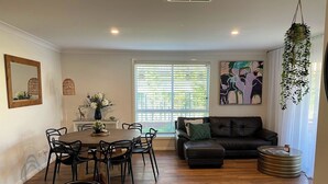 Uma sala de jantar com uma mesa redonda e cadeiras, um sofá e uma planta pendente.