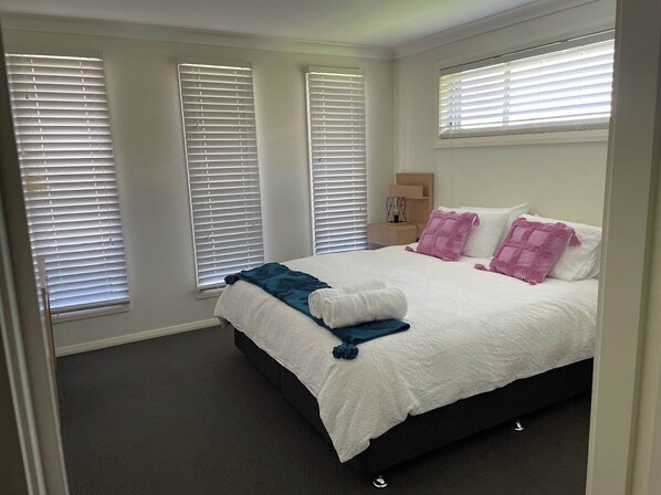 A bedroom with a bed, white walls, and windows with blinds. - On the Park-Modern 4 Bedroom 3 living Area Home 100m to Parks a& Shopping Centre (Dubbo)