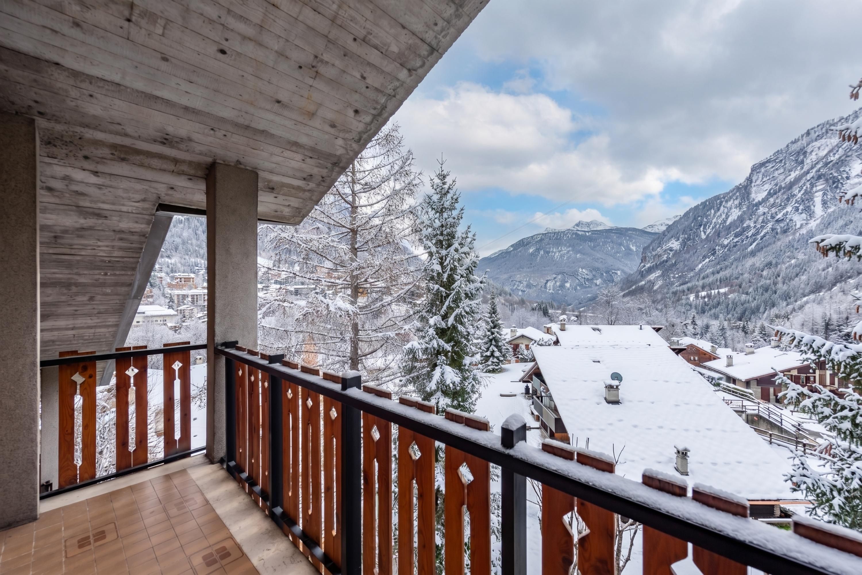 Een balkon met uitzicht op besneeuwde bergen en een stad op de achtergrond.