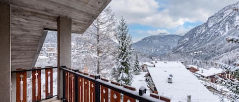 Ein Balkon mit Blick auf schneebedeckte Berge und eine Stadt im Hintergrund.