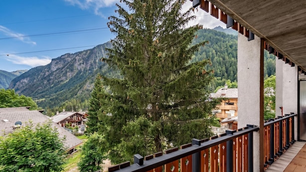 A balcony with a view of a mountain landscape, wooden railings, and a building with a sloped roof. - Residence Dolonne, Courmayeur, Italy (Courmayeur)