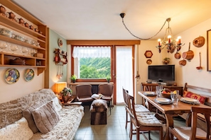 A cozy living room with a sofa, chairs, a dining table, and a TV.