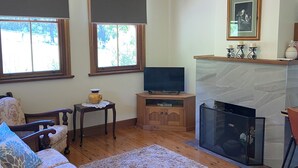 A living room with a sofa, a television, a fireplace, and a large window.