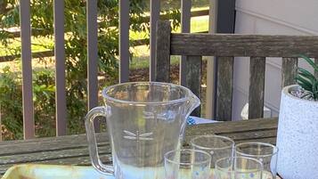 A tray with a pitcher and glasses on a wooden table outdoors.
