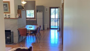 A spacious kitchen with a dining area, wooden flooring, and a view through the door.