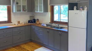 A modern kitchen with grey cabinets, a white refrigerator, and a wooden countertop.