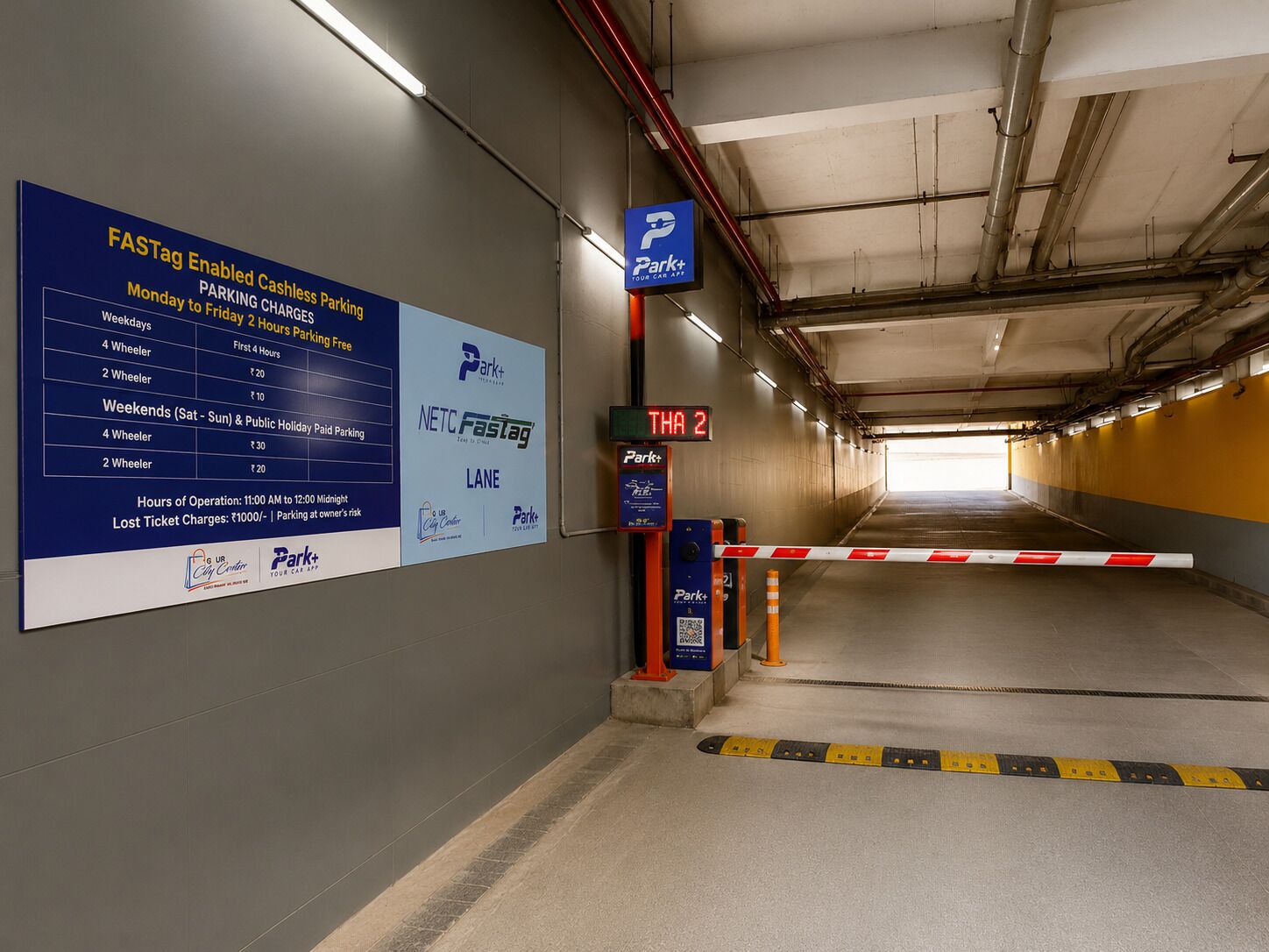 A parking garage with FASTag-enabled cashless parking signs, a Park+ sign, and a lane indicator.
