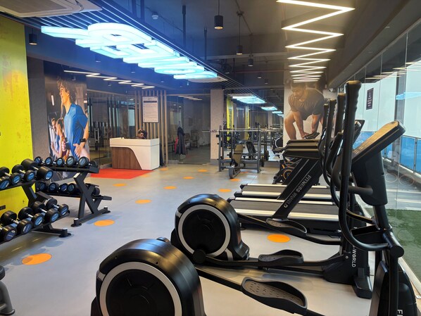 A gym with treadmills, dumbbells, and weight machines.
