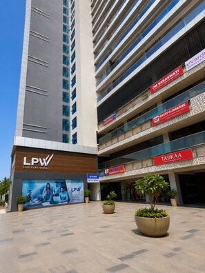 Un edifici modern amb diversos pisos, un distintiu senyalitzador LPW Live Play Work, i diverses botigues comercials, incloent-hi una botiga anomenada TADKAA.