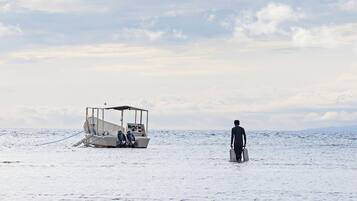 Un bateau est amarré dans des eaux calmes, et une personne qui porte une valise s’en approche.
