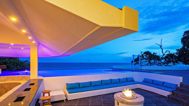 A modern outdoor seating area with a fire feature, a pool, and a view of the ocean. - Dive Spot Asia & Brumini Beach Resort (Boljoon)