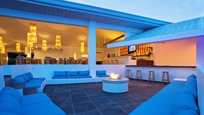 A modern outdoor seating area with a fire pit, bar, and large windows. - Dive Spot Asia & Brumini Beach Resort (Boljoon)
