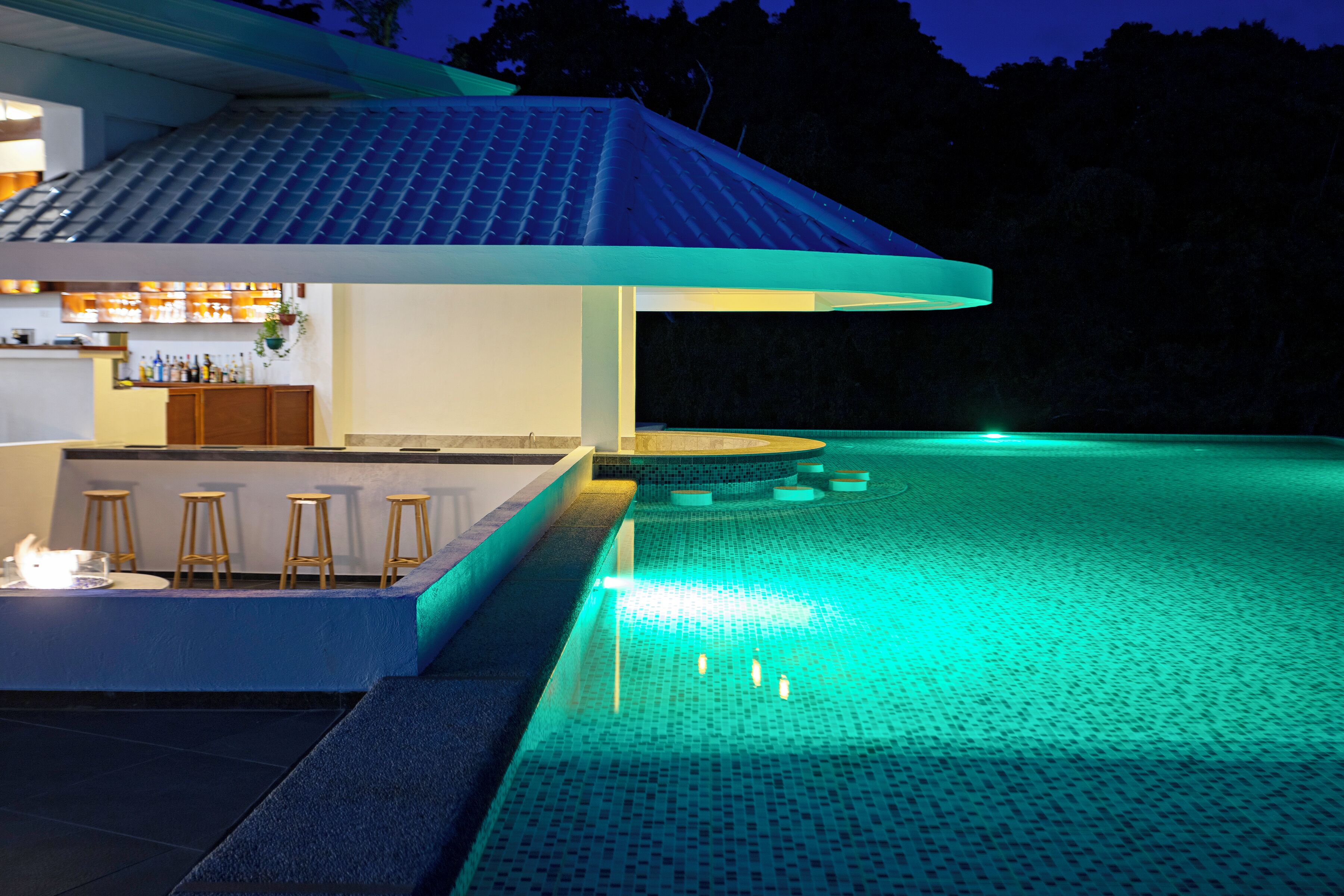 A swimming pool with a bar area and stools.