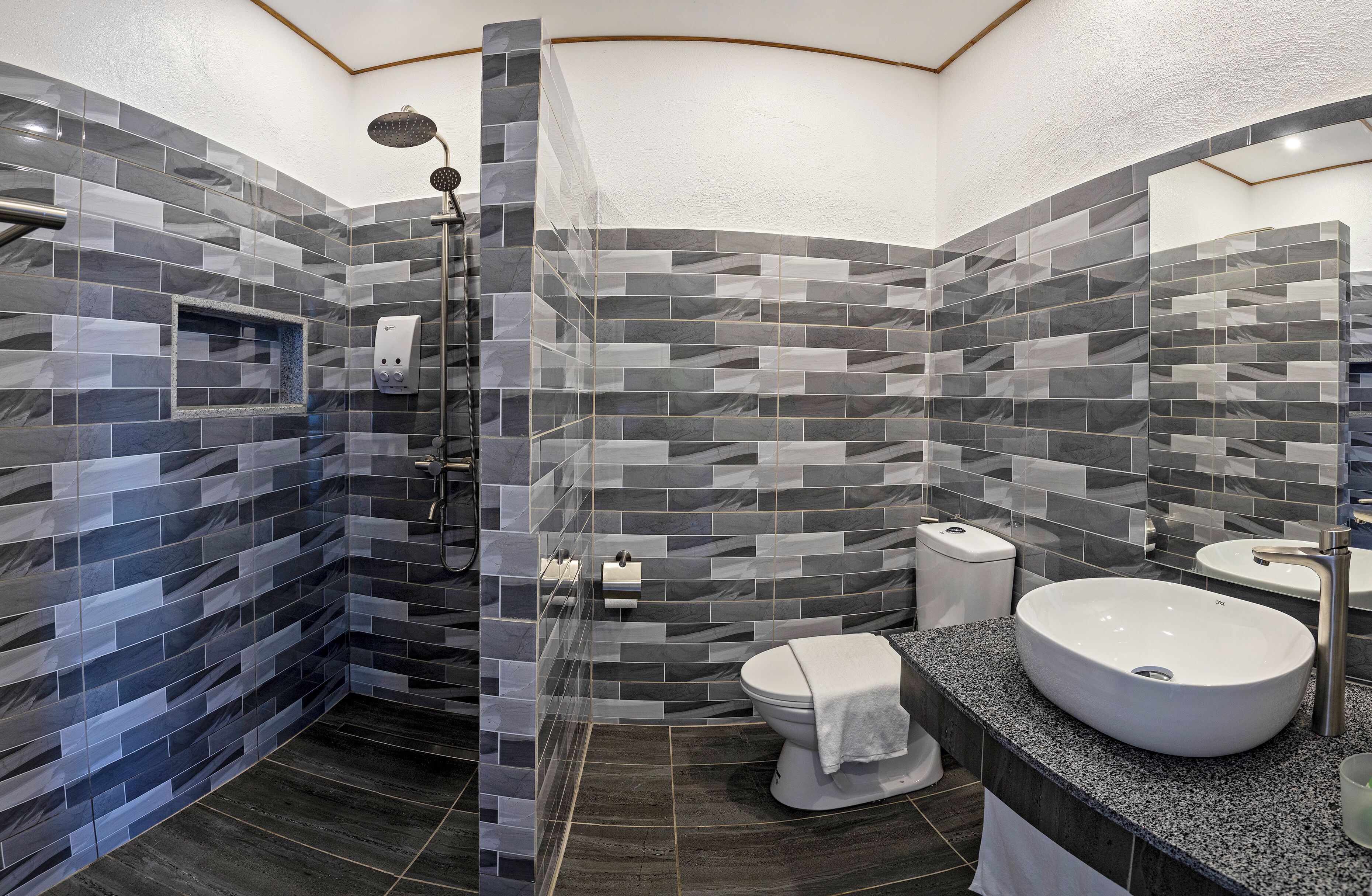 Un baño moderno con ducha de vidrio, inodoro blanco y un lavamanos grande con encimera de mármol.