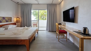 A hotel room with a bed, a desk, a chair, a TV, and a view of the outdoors. - Dive Spot Asia & Brumini Beach Resort (Boljoon)