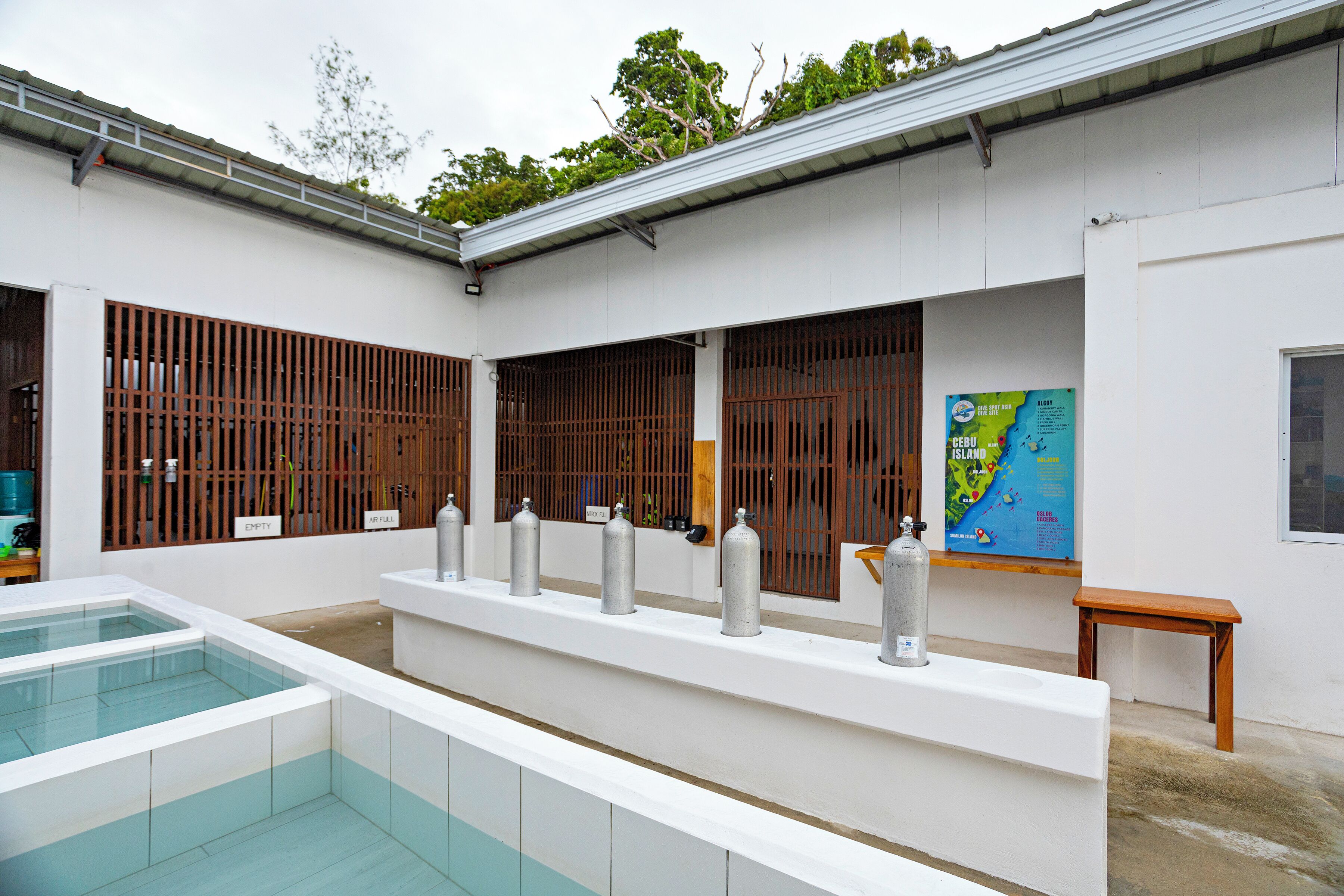 A clean, modern indoor pool area with a long bench and several gas cylinders.