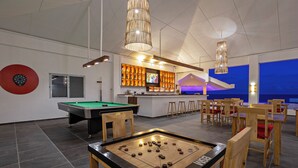 A billiards table, a pool table, and a foosball table in a room with a bar area and seating. - Dive Spot Asia & Brumini Beach Resort (Boljoon)